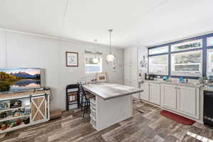 Kitchen area featuring white cabinetry, light countertops, and a wood-finish island with seating