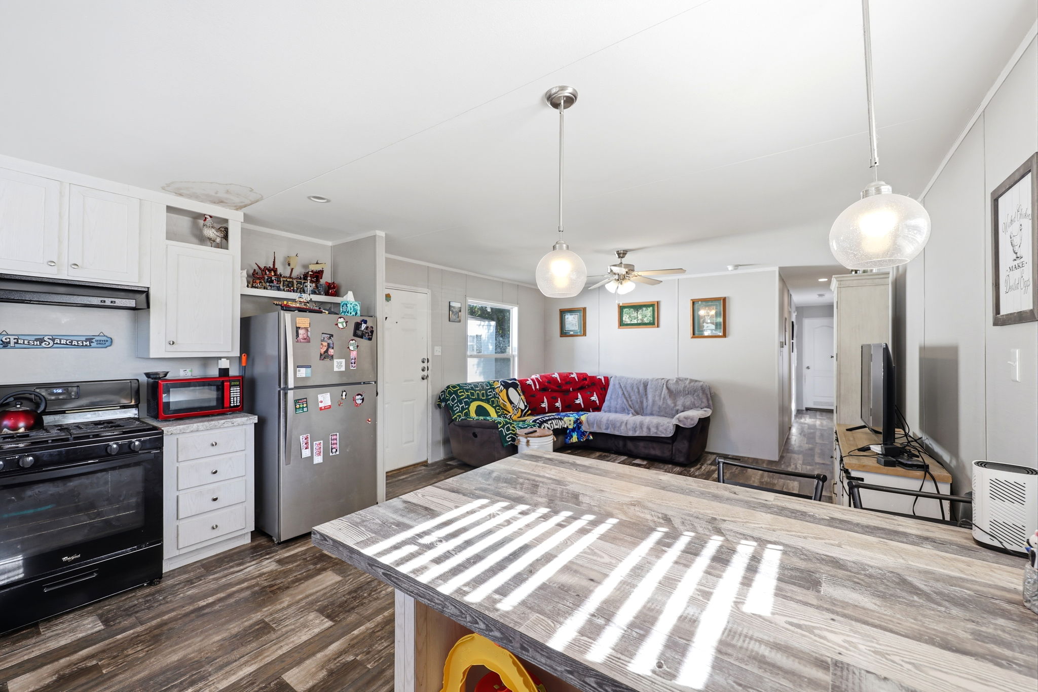 Open-concept living space featuring wood-finish flooring, white cabinetry, and stainless steel appliances