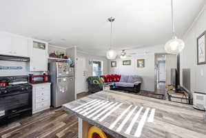 Open-concept living space featuring wood-finish flooring, white cabinetry, and stainless steel appliances