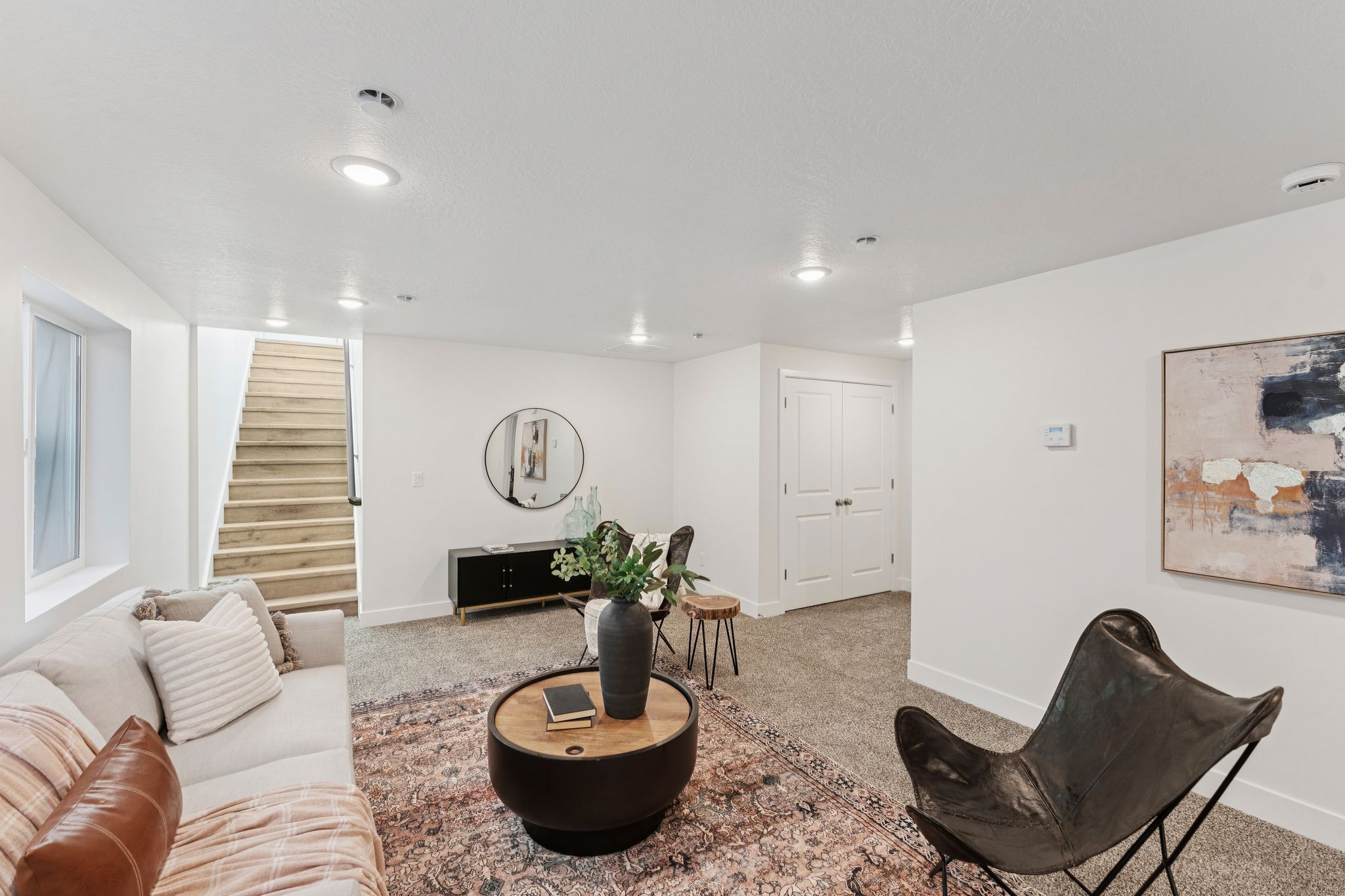 Carpeted living area featuring recessed lighting, a window, wood-finish stairs, and double panel doors