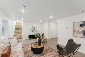 Carpeted living area featuring recessed lighting, a window, wood-finish stairs, and double panel doors