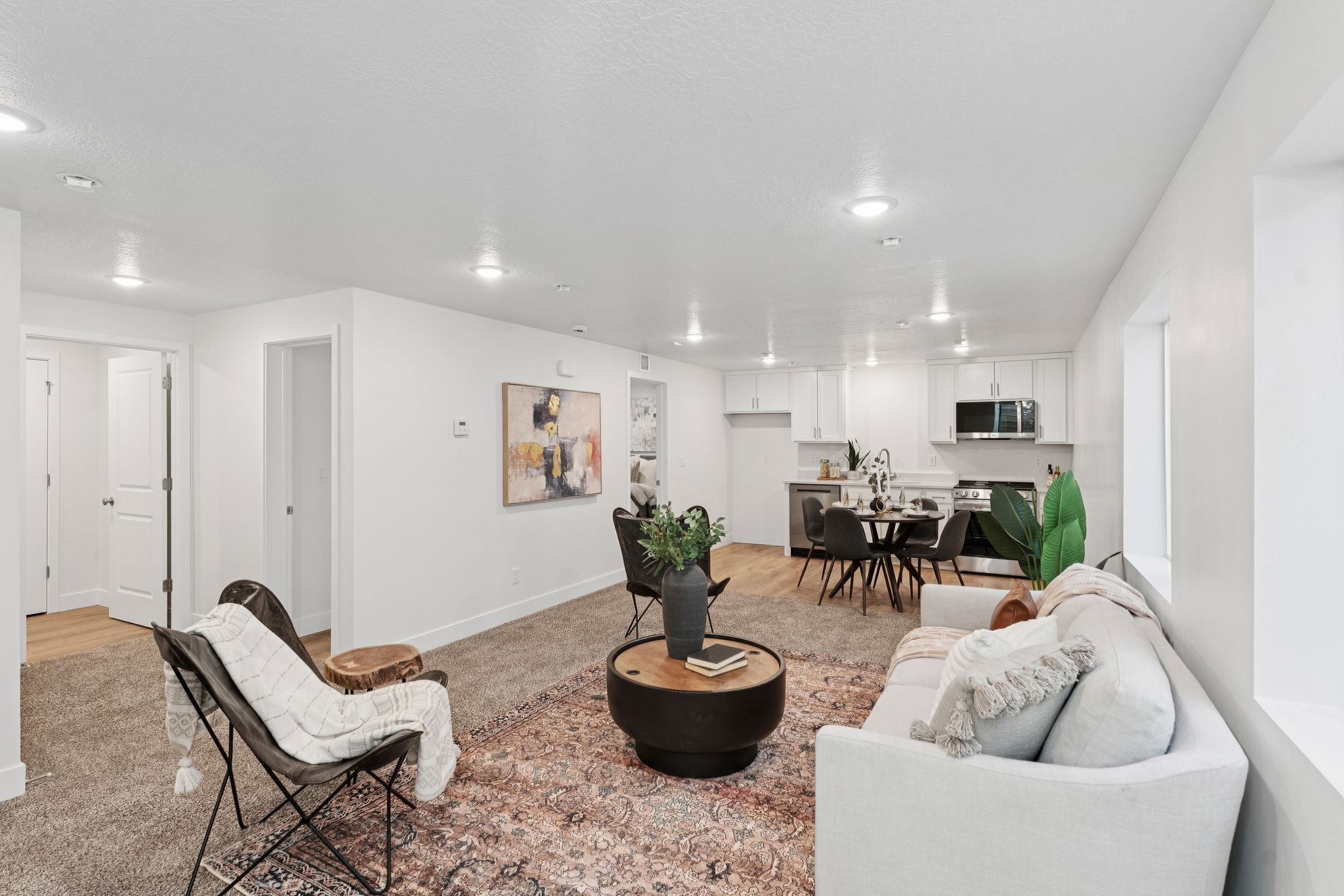 Open-concept living space featuring recessed lighting, a kitchen with white cabinetry, a dining area, and wood-finish flooring