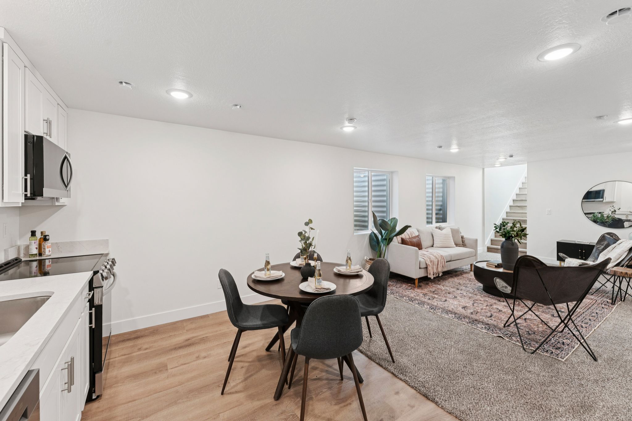 Integrated living space featuring white kitchen cabinetry, stainless steel appliances, and wood-finish flooring