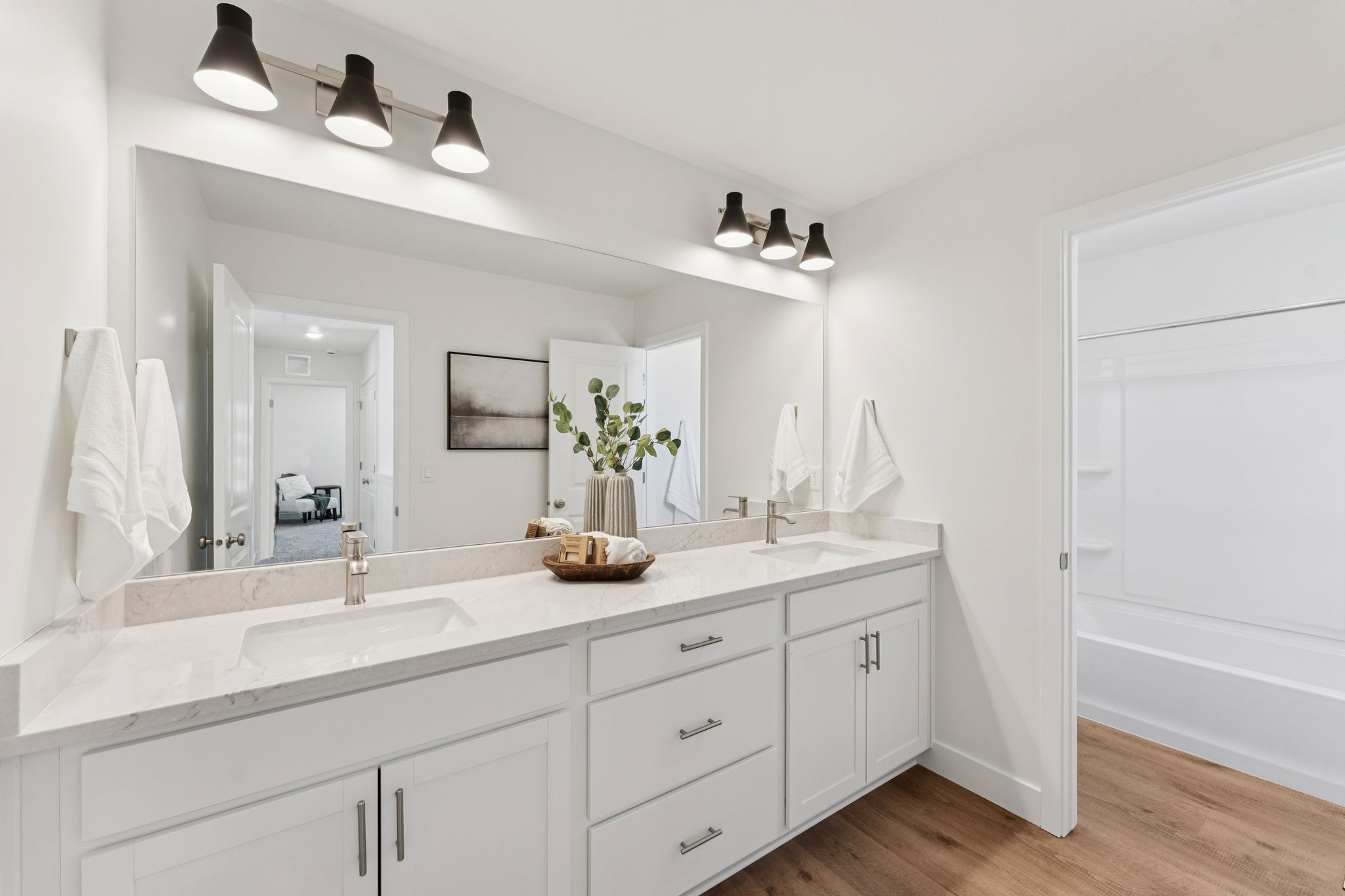 Dual vanity featuring integrated sinks, light-toned countertops, and white shaker-style cabinetry with chrome hardware