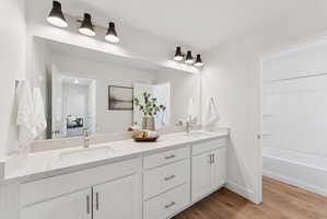 Dual vanity featuring integrated sinks, light-toned countertops, and white shaker-style cabinetry with chrome hardware