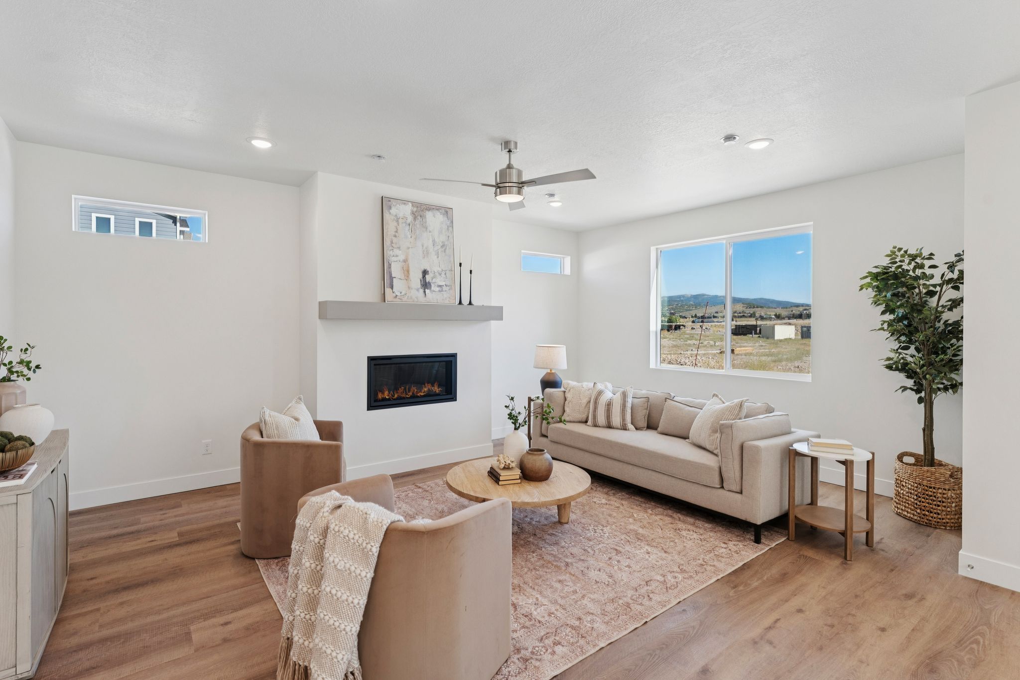 Spacious living area featuring a modern fireplace with a light gray mantel, recessed lighting, and wood-finish flooring