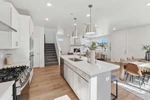 Gourmet kitchen featuring a gas range, built-in microwave and oven, shaker cabinetry, and a large island with a stainless steel sink
