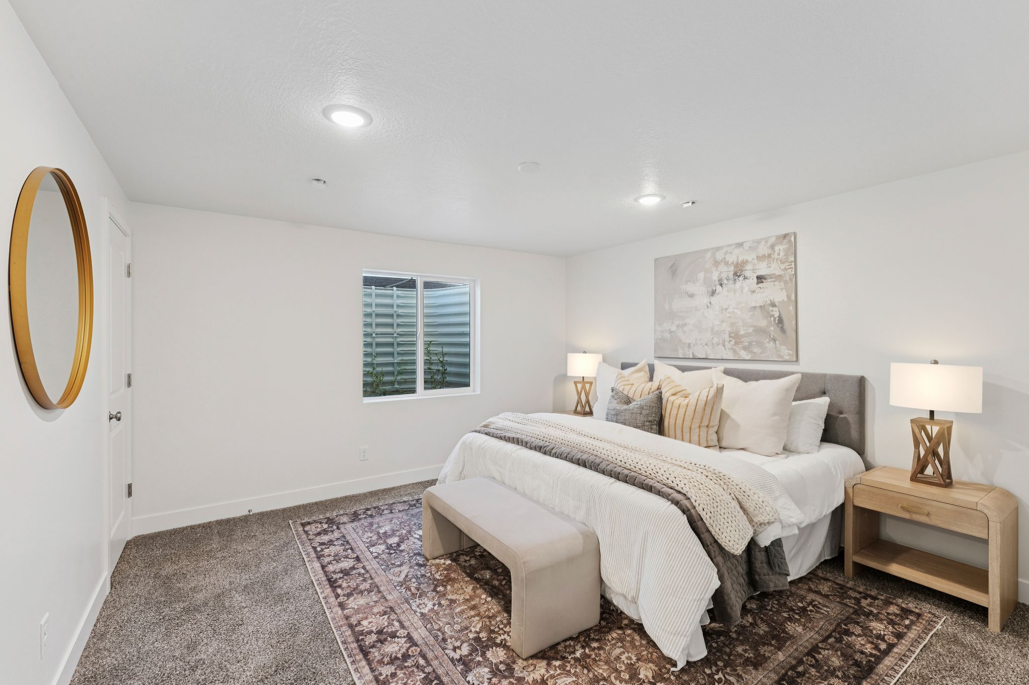 Spacious bedroom featuring neutral wall tones, recessed lighting, a large area rug, and a window with a well-grated exterior
