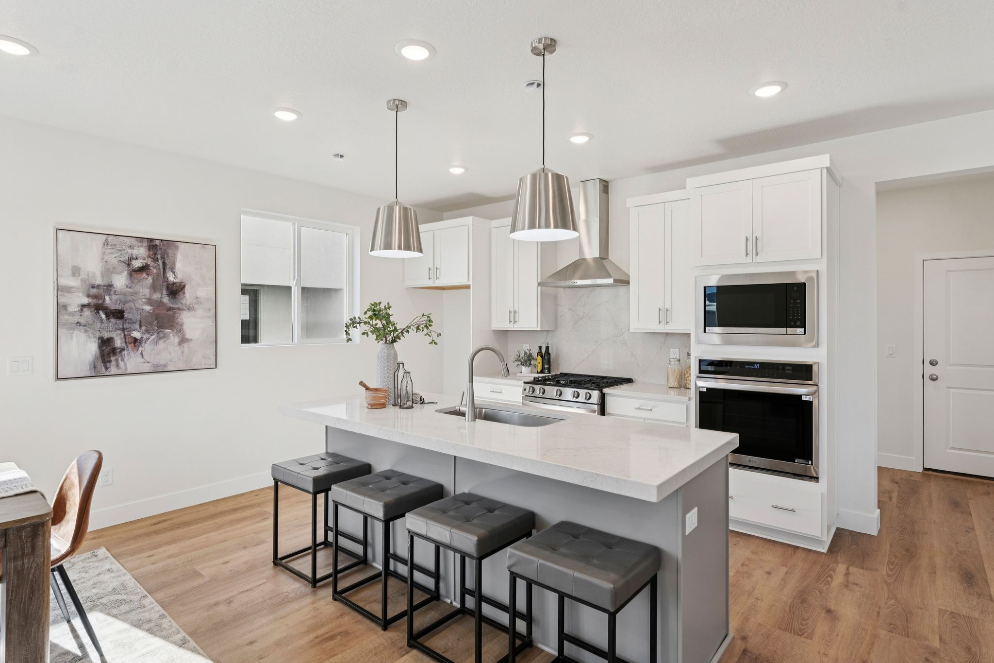 Modern kitchen featuring a central island with countertop seating, stainless steel appliances, white cabinetry, and wood-finish flooring
