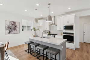 Modern kitchen featuring a central island with countertop seating, stainless steel appliances, white cabinetry, and wood-finish flooring