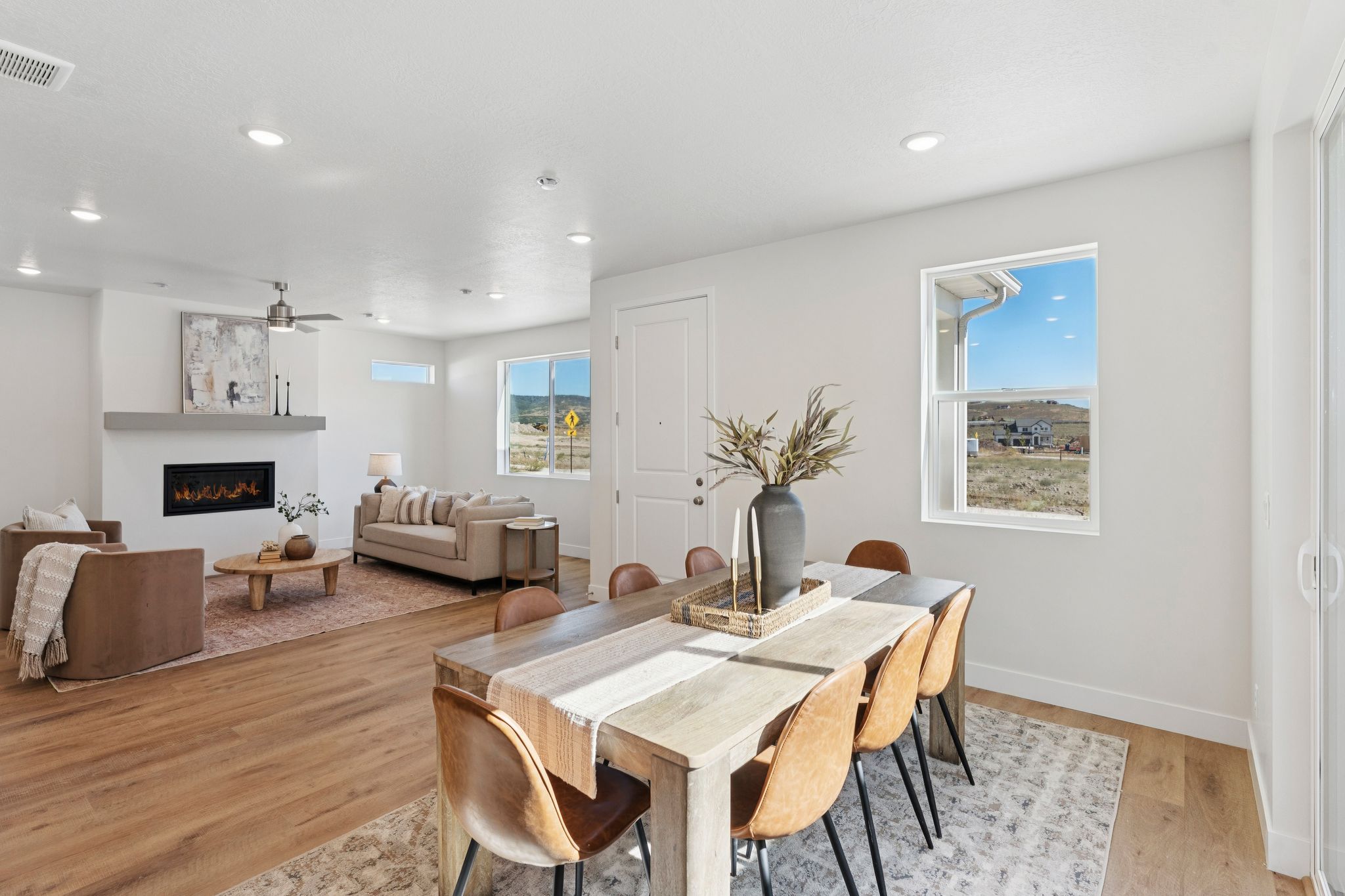 Open-concept dining and living area featuring wood-finish flooring, recessed lighting, and white walls