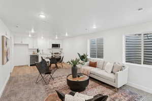 Open-concept living space featuring recessed lighting, a modern kitchenette with white cabinetry, and wood-finish flooring in the kitchen area