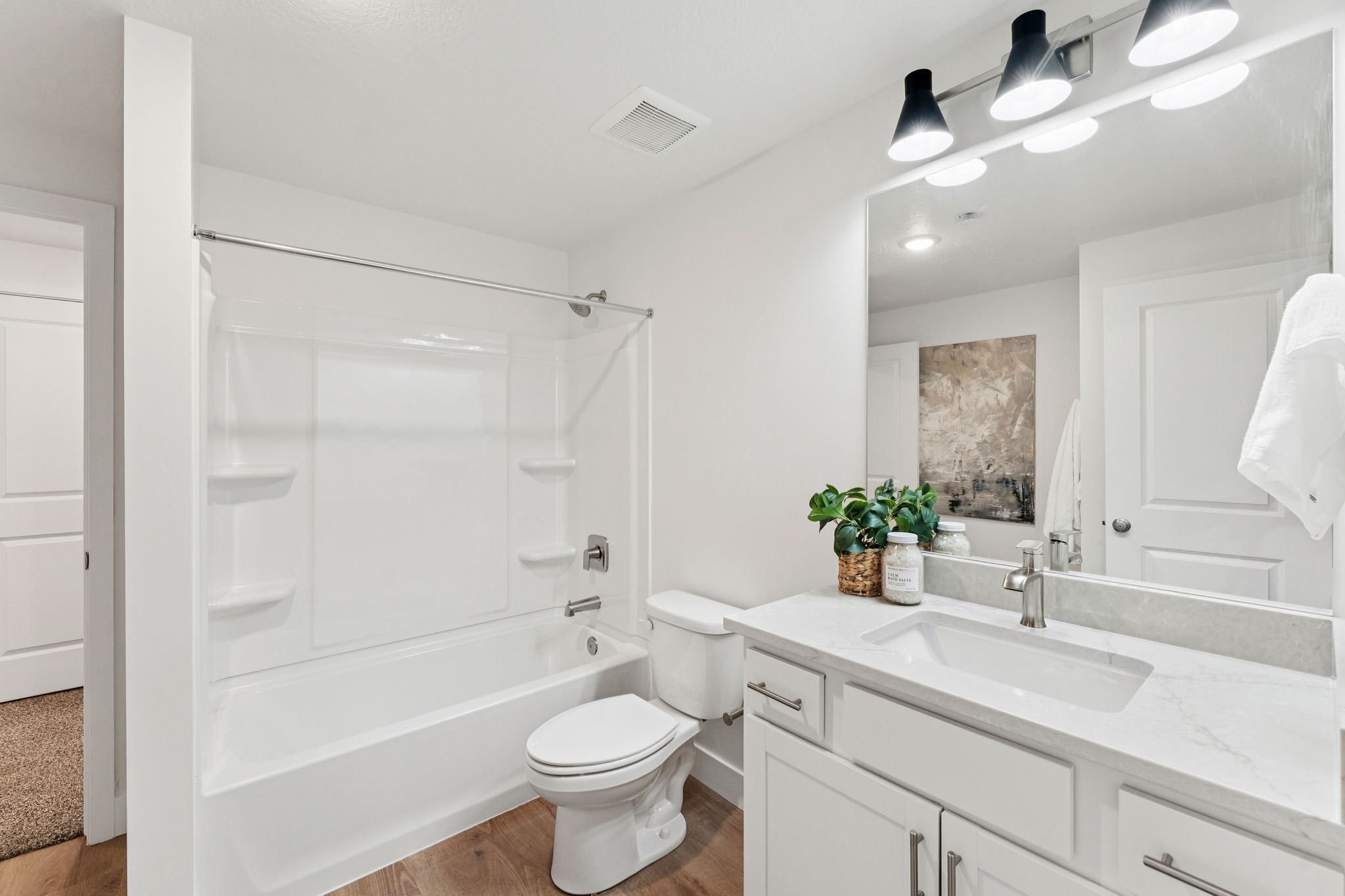 Modern bathroom featuring a white vanity with an integrated sink, a large mirror, and contemporary overhead lighting