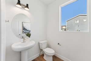 Pedestal sink with a brushed nickel faucet, an oval mirror, and a two-bulb wall sconce