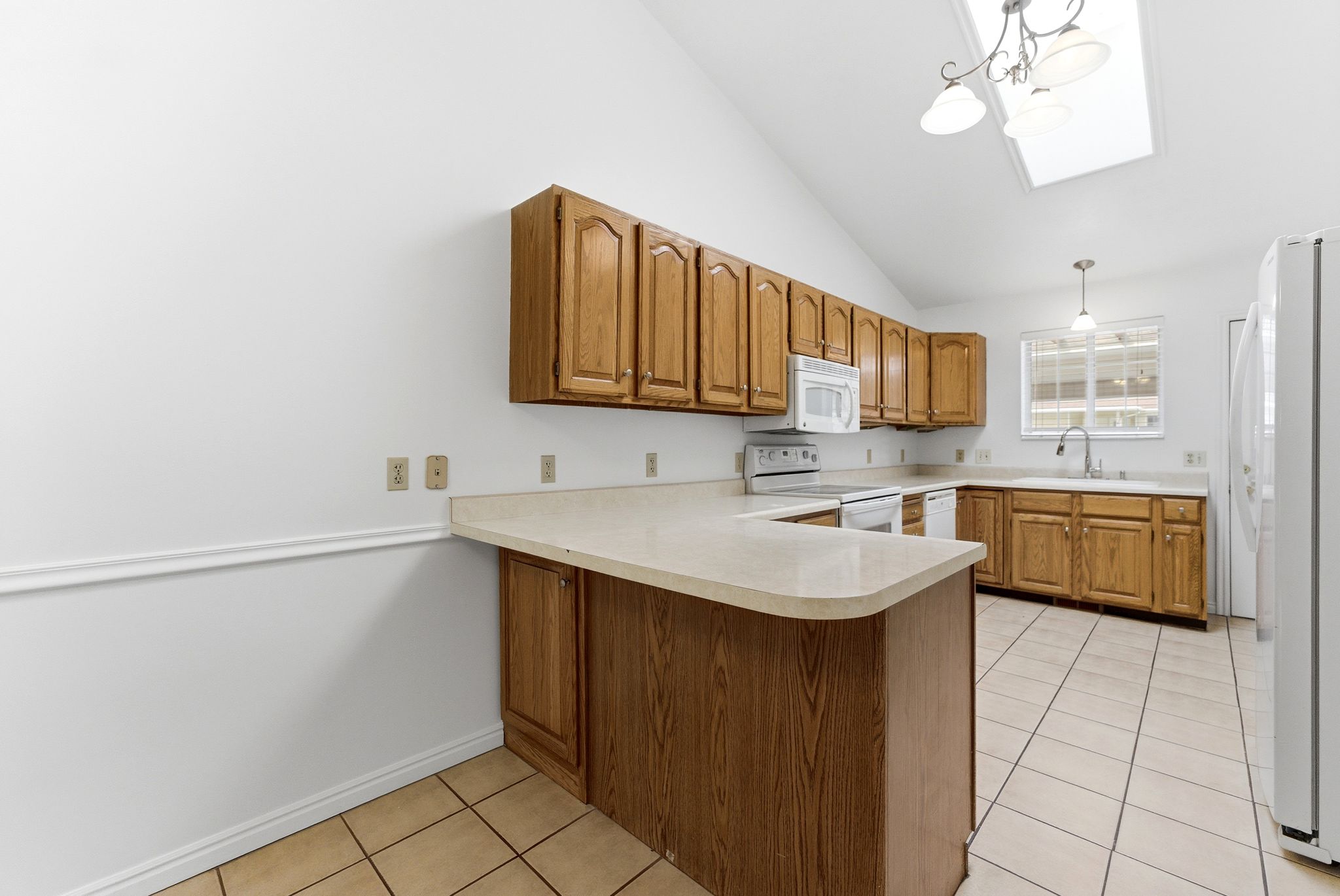 Kitchen featuring wood cabinetry, light-toned countertops, and tile flooring
