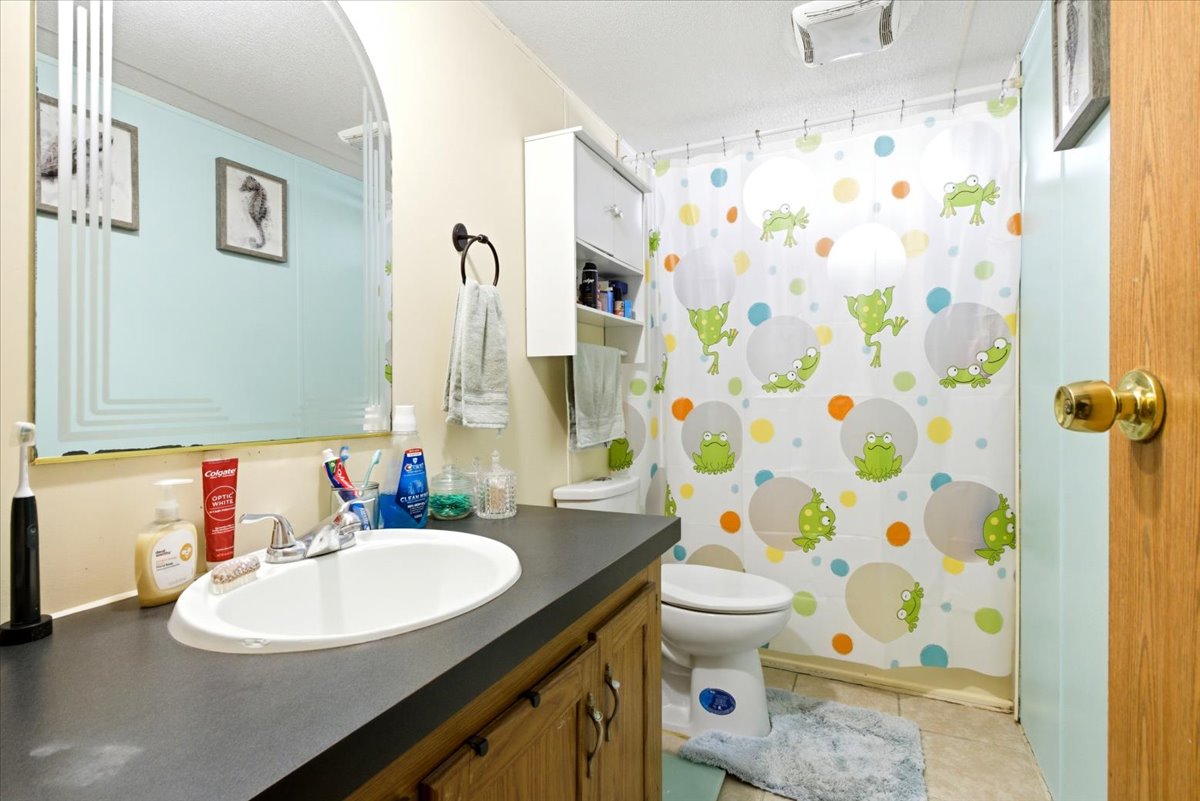 Bathroom featuring a vanity with an integrated sink, dark countertop, and wood-finish cabinetry