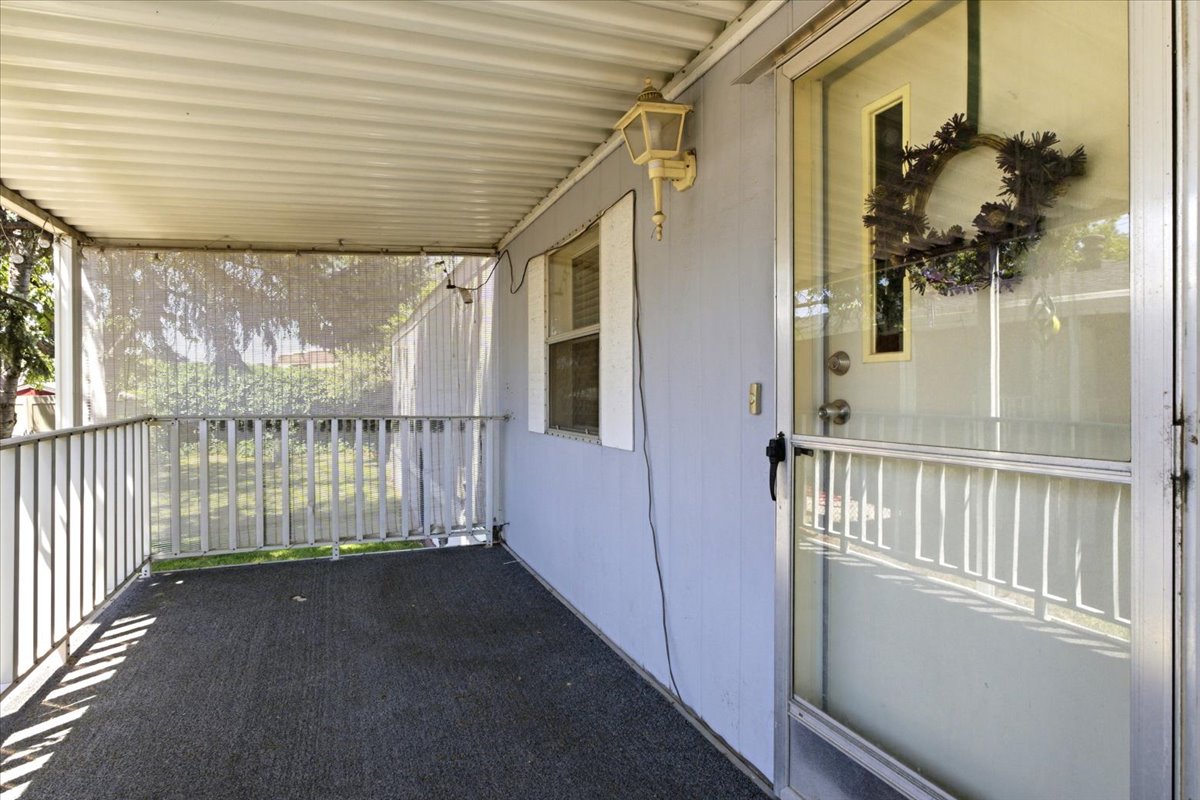 Covered porch featuring a corrugated ceiling, light blue siding, and an aluminum railing