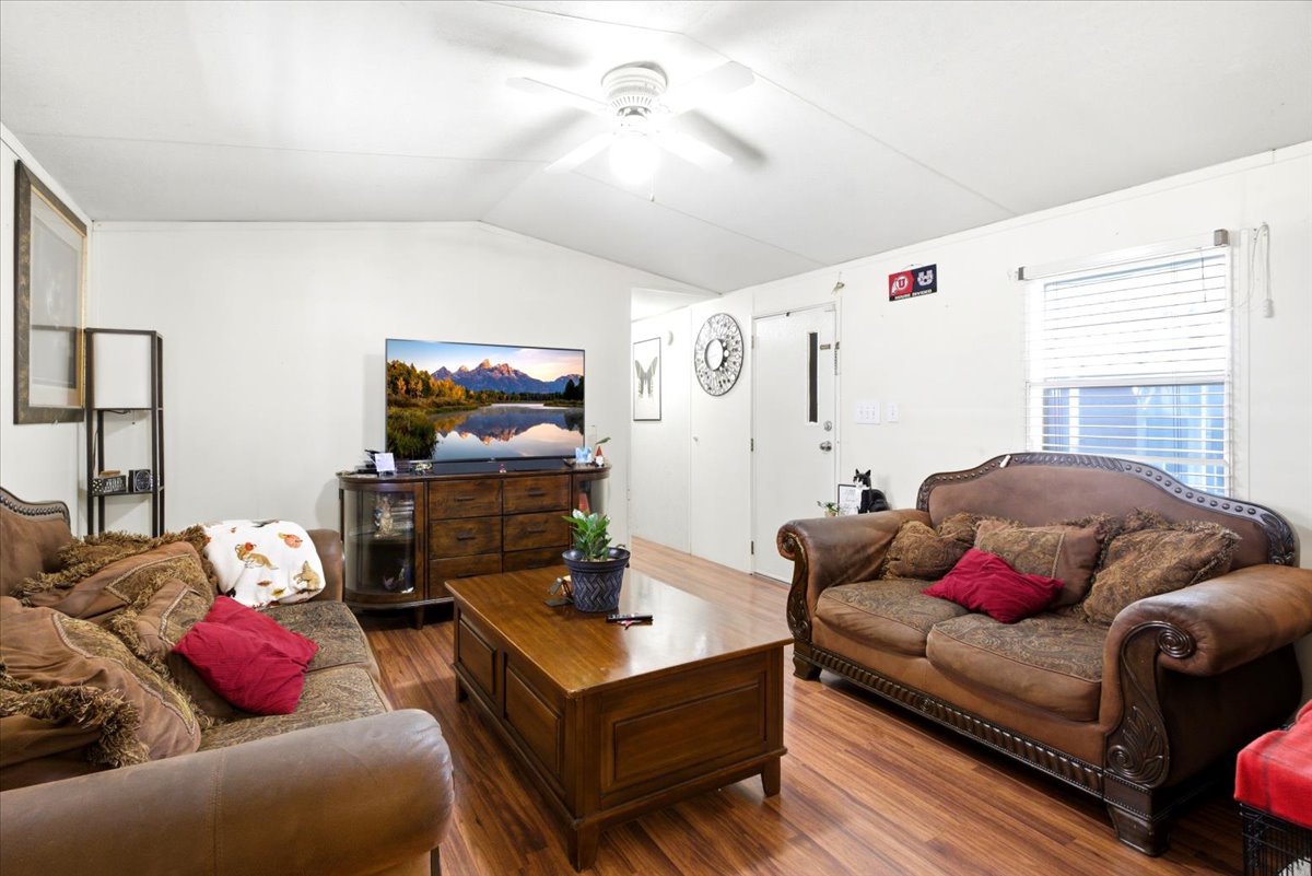 Living area featuring wood-finish flooring, white walls, and a white ceiling with a ceiling fan