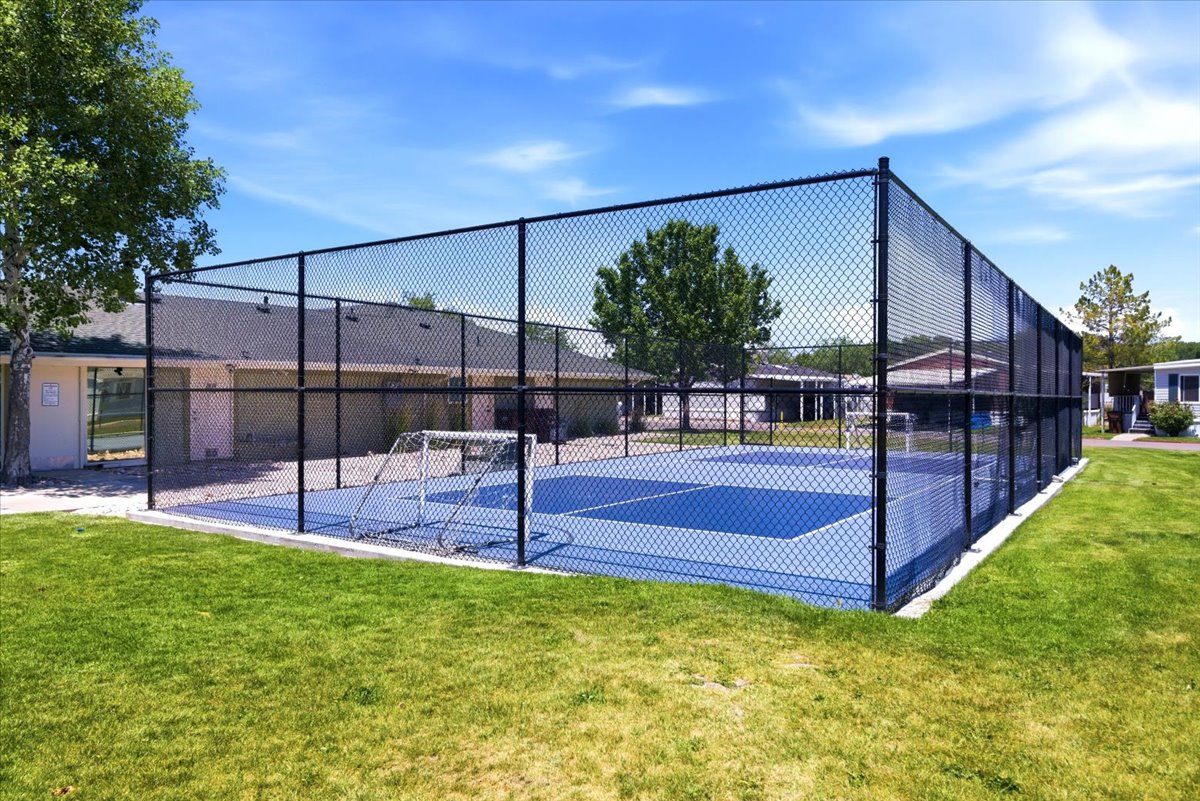 Fenced sports court with a blue playing surface and white line markings
