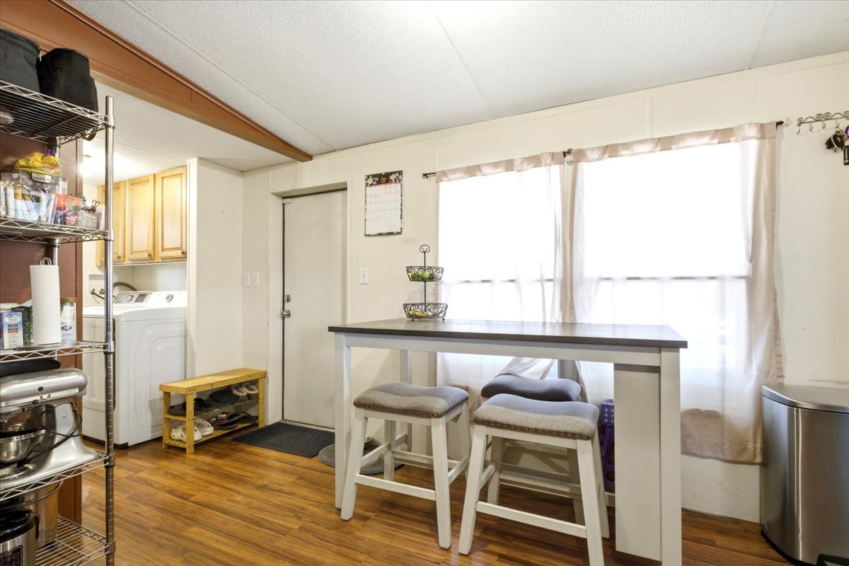 Spacious dining area featuring wood-finish flooring, two large windows, and a white door