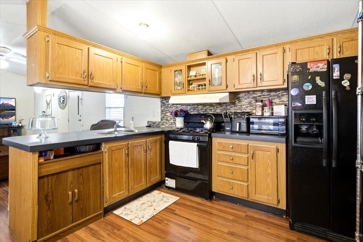 Kitchen featuring wood-finish flooring, a mosaic tile backsplash, wood cabinetry, and laminate countertops
