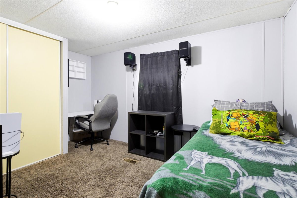 Carpeted room featuring a built-in desk, light-colored sliding closet doors, and light-toned wall paneling