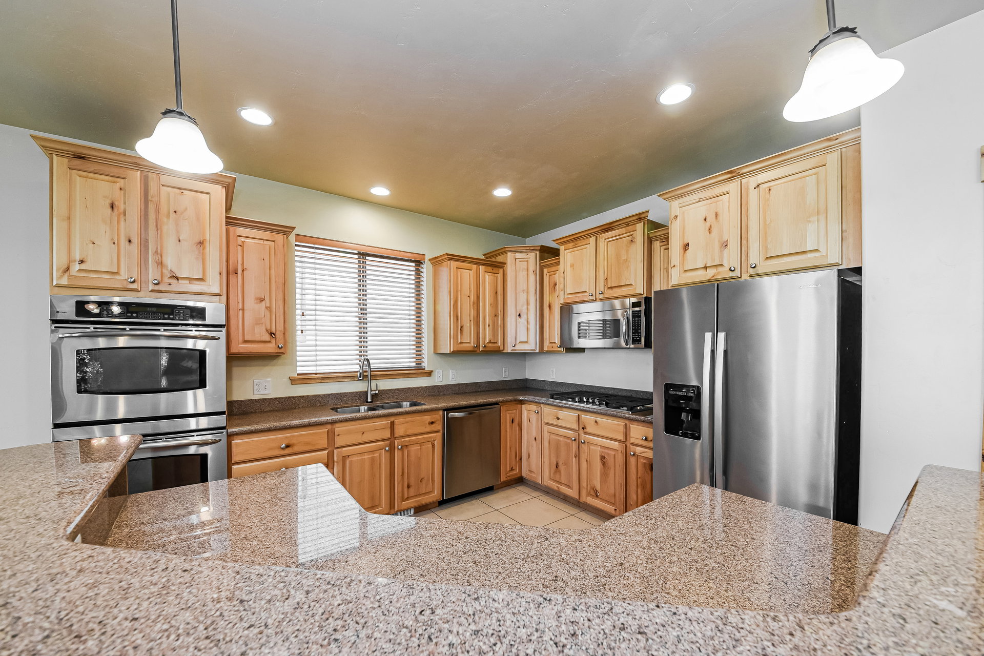 Kitchen featuring wood cabinetry, stainless steel appliances, and granite-look countertops