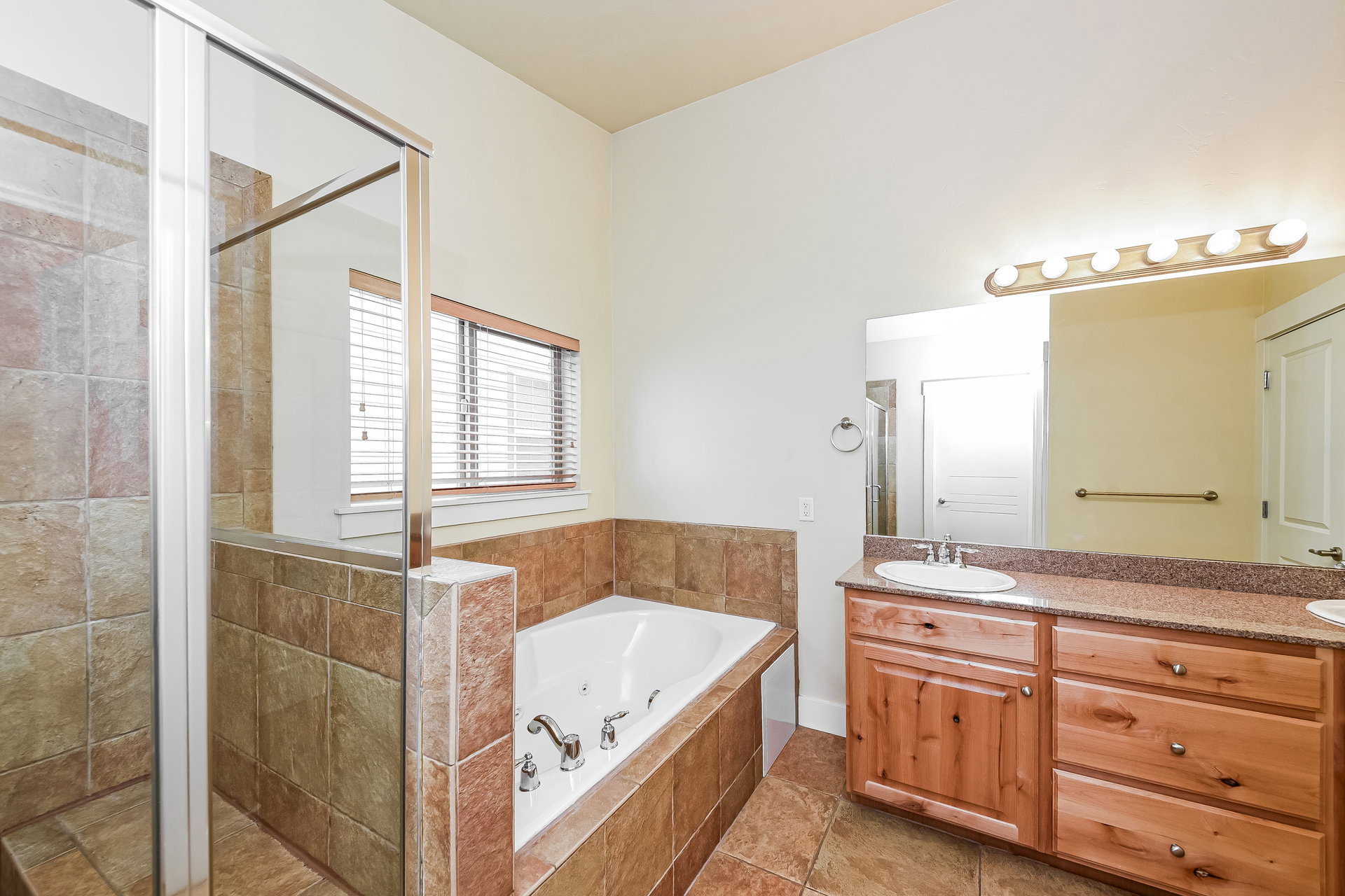 Bathroom featuring a tiled soaking tub and a separate glass-enclosed shower