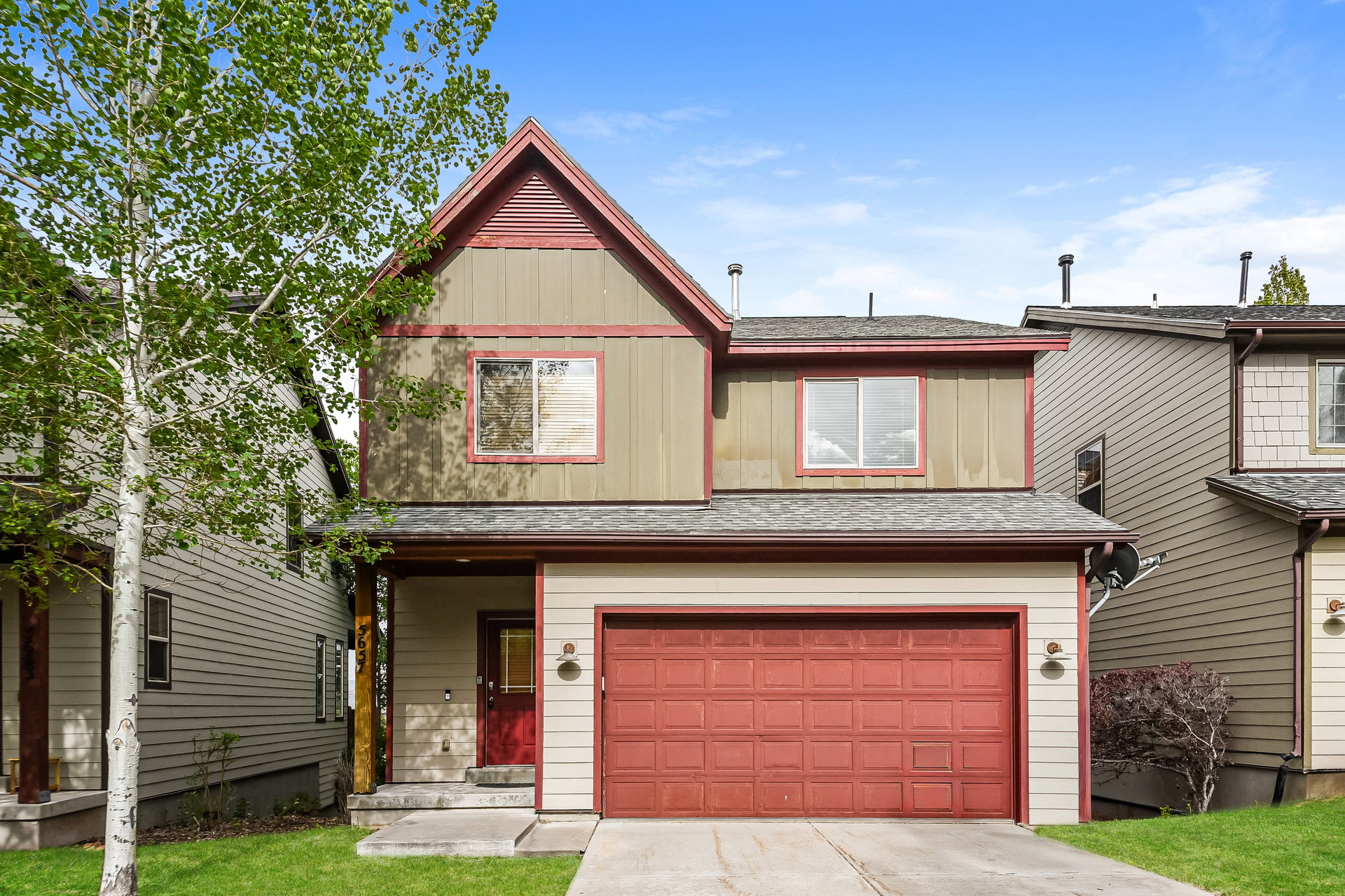 Two-story residence featuring a prominent red garage door and a complementary red front door