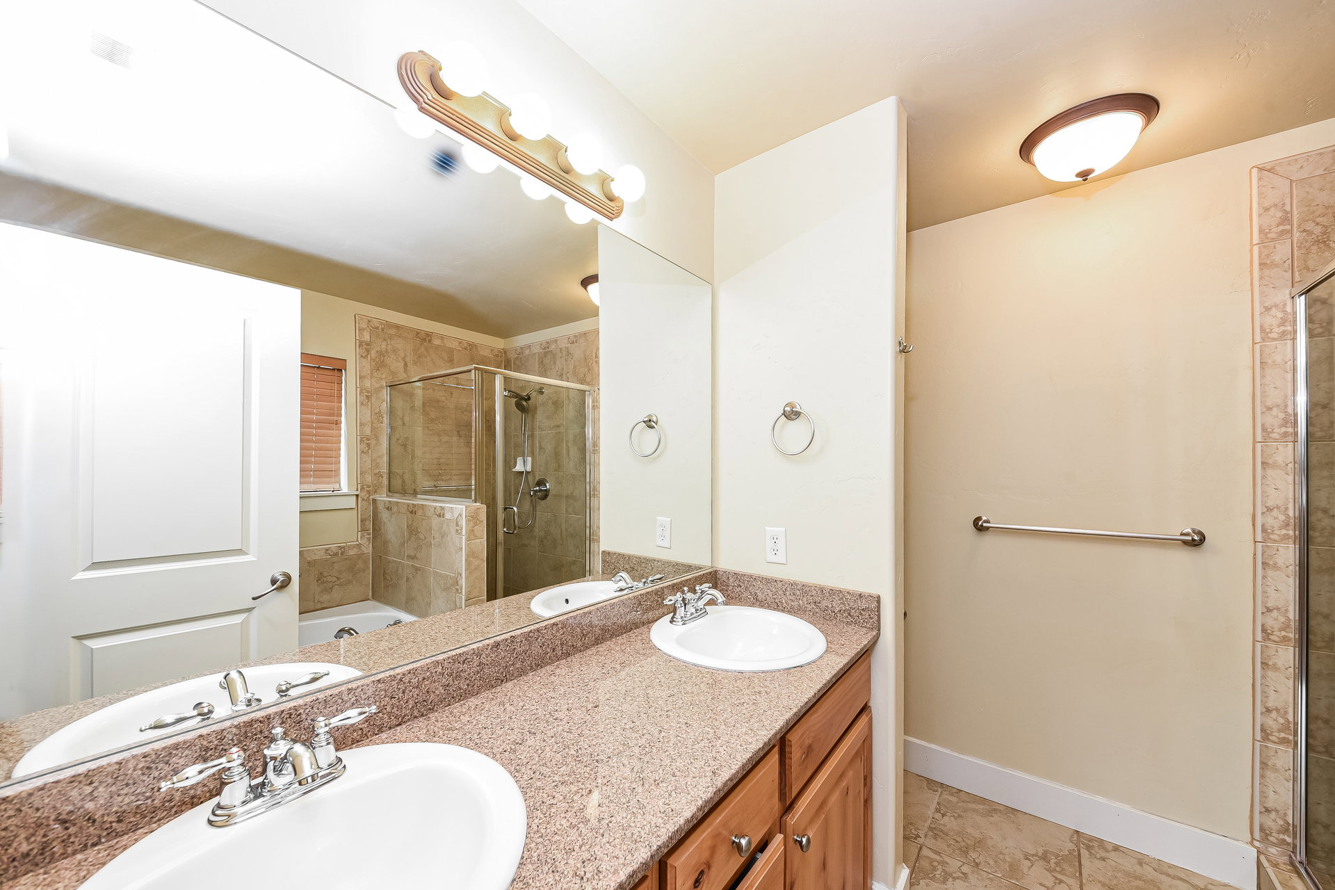 Dual vanity with integrated sinks, granite-finish countertop, and wood-finish cabinetry