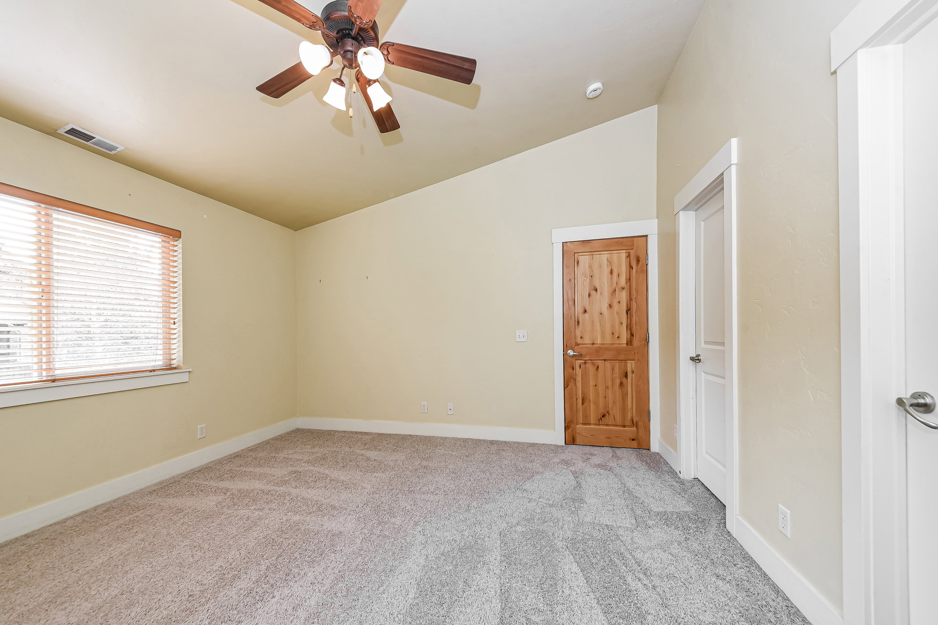 Room featuring vaulted ceilings, neutral wall tones, and plush carpet flooring