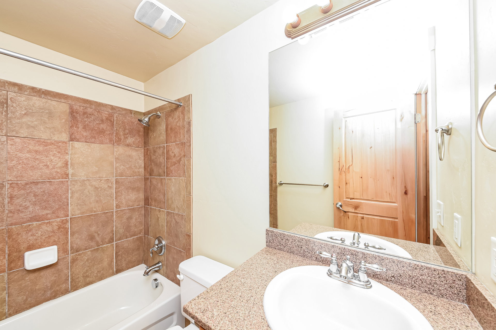 Bathroom featuring a shower-over-tub combination with tile surround, white porcelain toilet, vanity with integrated sink, and granite-finish countertop