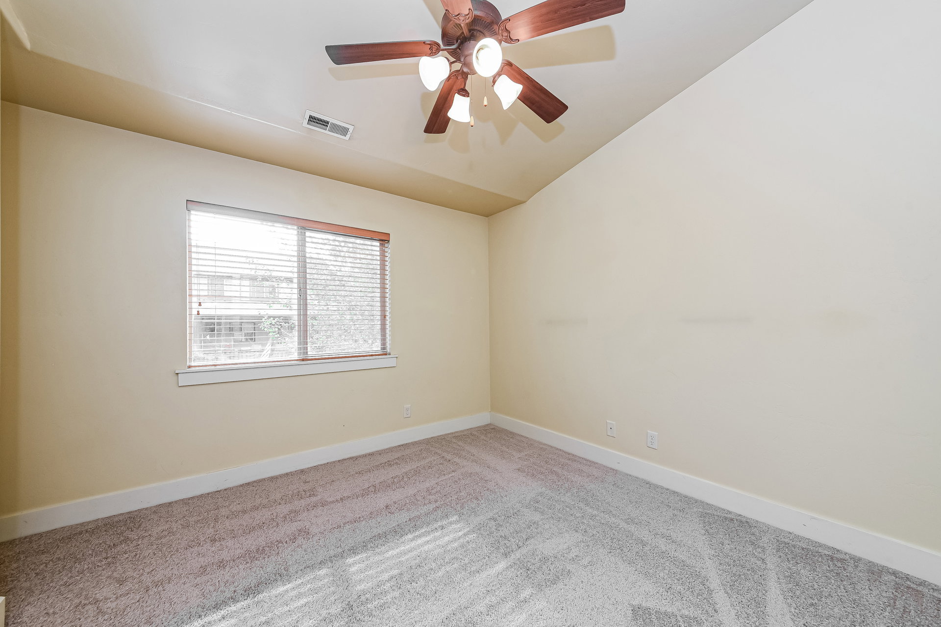 Bedroom featuring vaulted ceilings, a ceiling fan with integrated lighting, a window with blinds, light-colored walls, and patterned carpet flooring