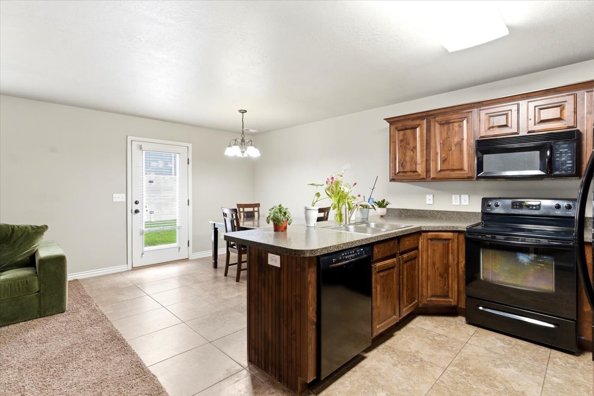 Kitchen featuring wood-finish cabinetry, black appliances, and a peninsula with integrated sink