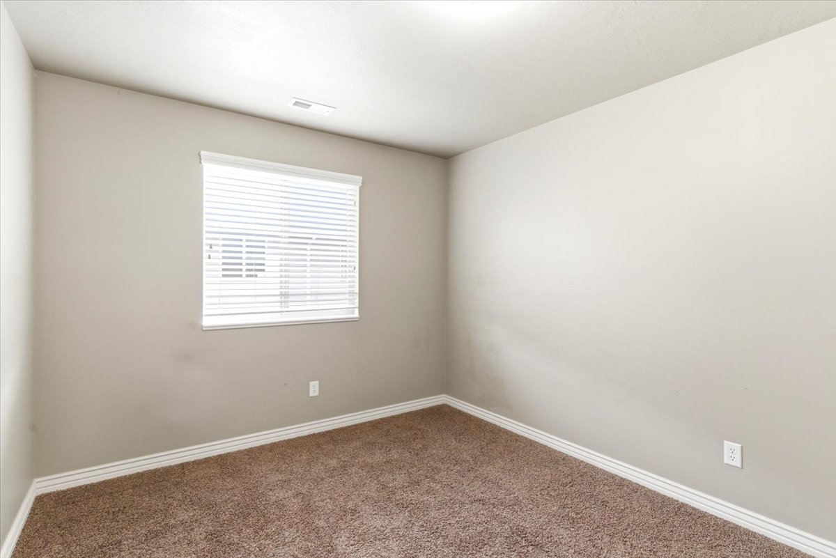 Neutral-toned wall paint with white trim, brown carpeting, and a window with horizontal blinds