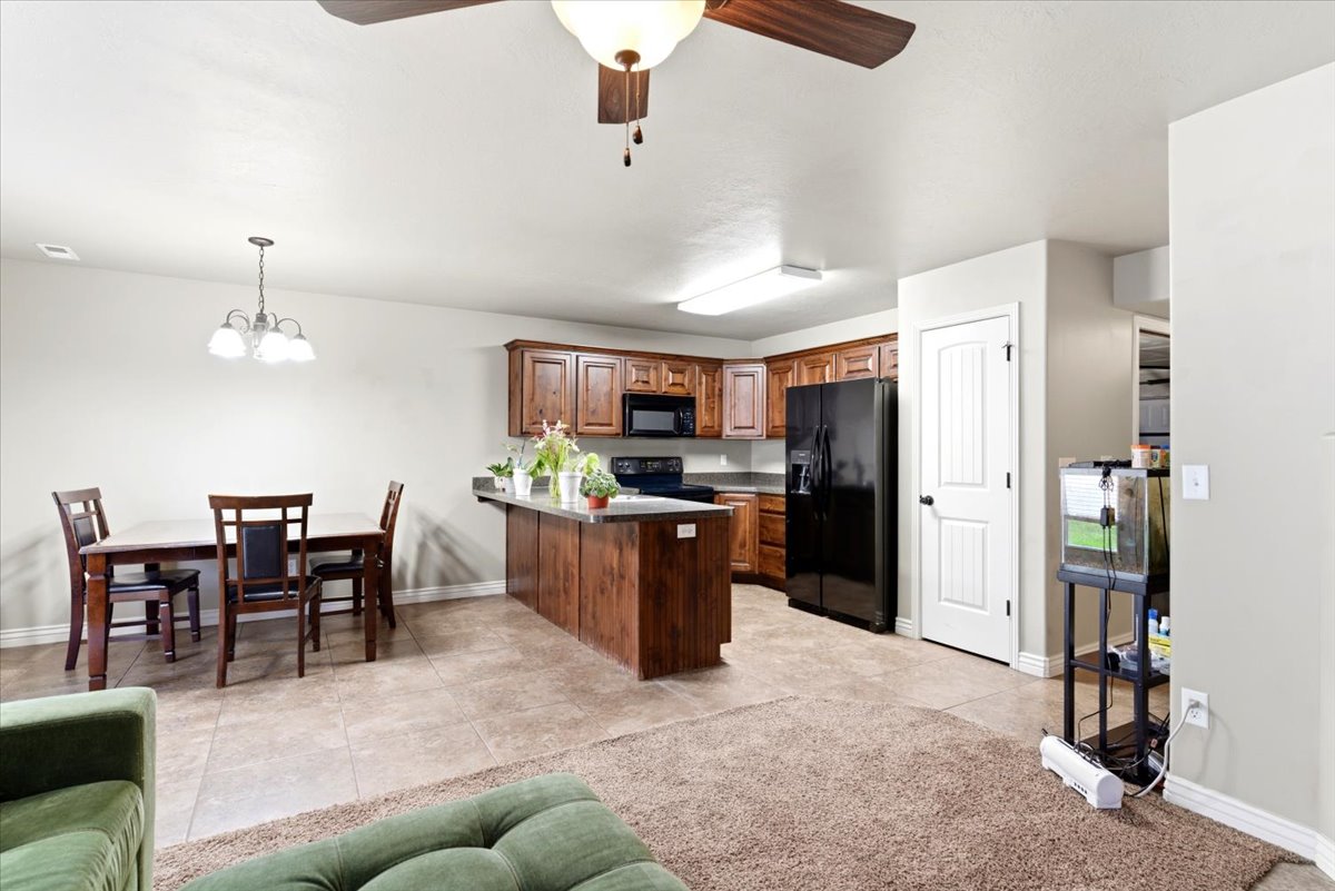 Open-concept living space featuring a kitchen with wood cabinetry, black appliances, and a central island