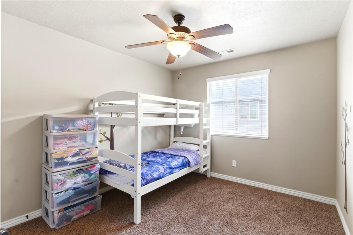 Carpeted room featuring a ceiling fan with integrated lighting, a window with blinds, and neutral painted walls