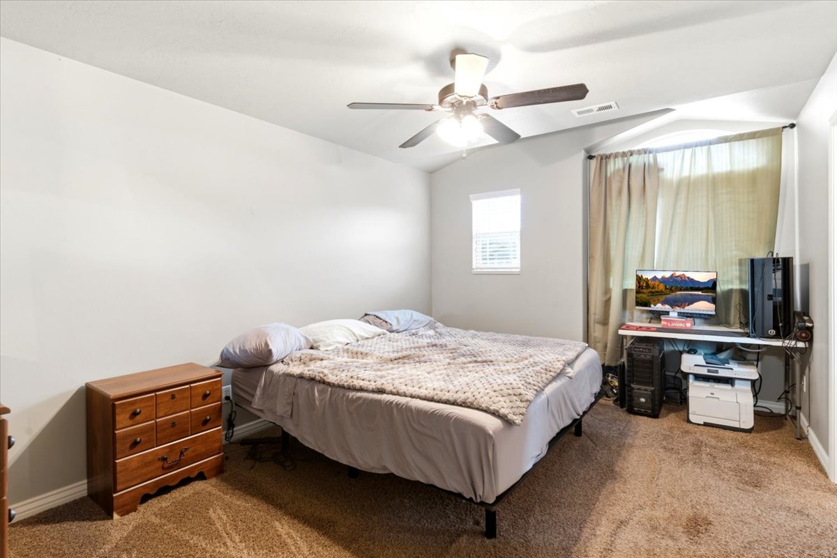 Carpeted room featuring a ceiling fan with integrated lighting, a single window with horizontal blinds, and neutral-toned wall paint
