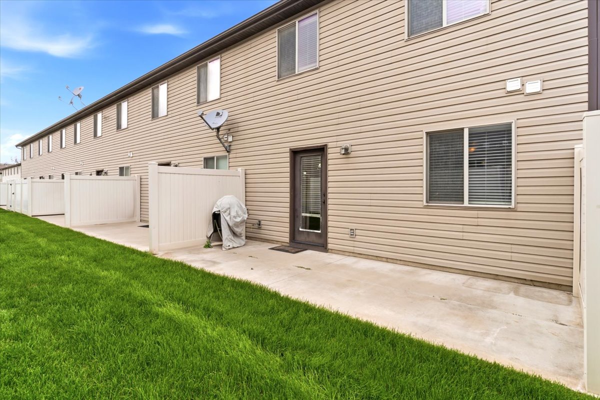 Rear exterior featuring durable siding, a private patio area, and a lush green lawn