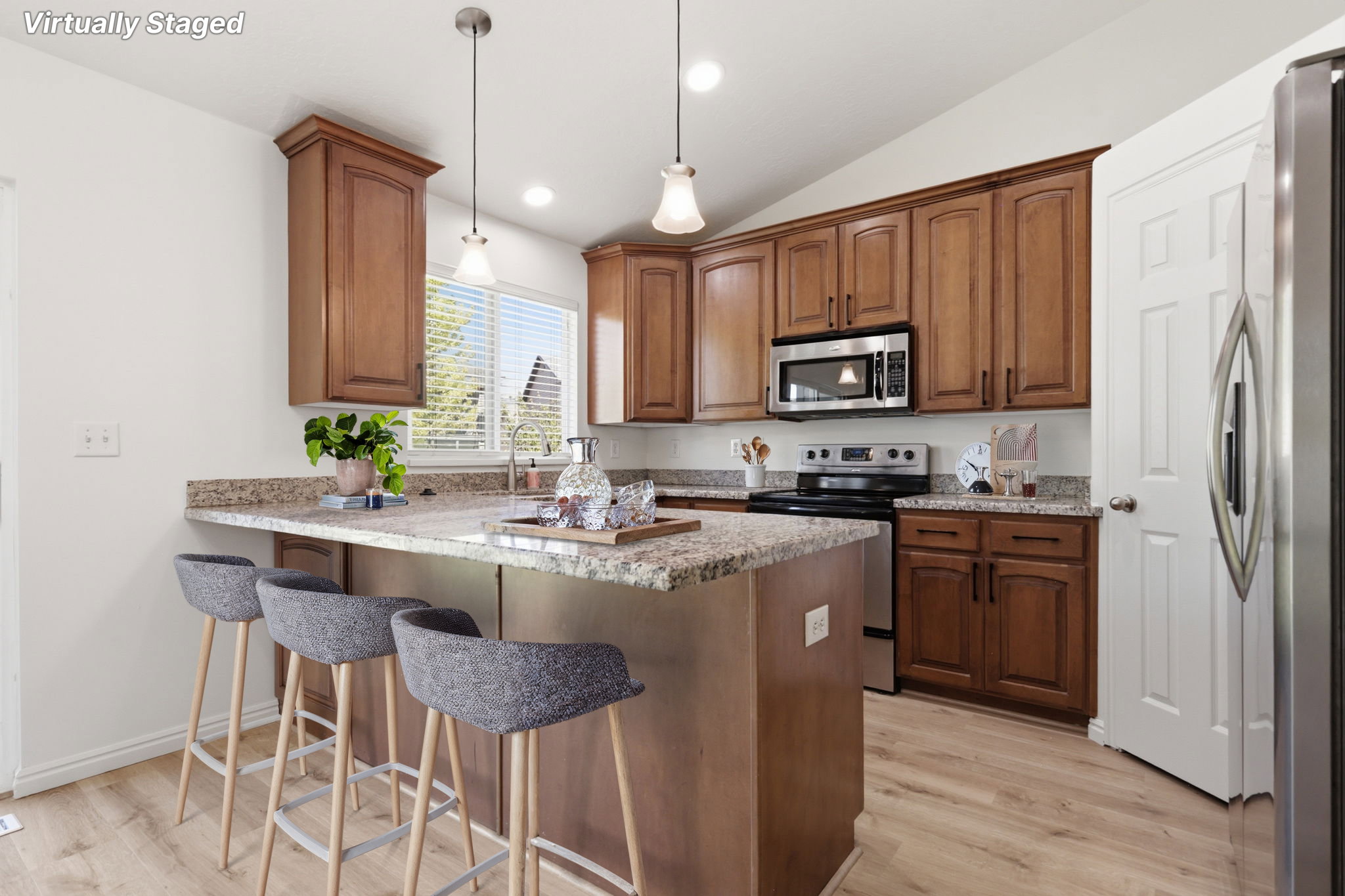 Kitchen featuring an island with a breakfast bar, wood-finish flooring, granite countertops, wood cabinetry, and stainless steel appliances