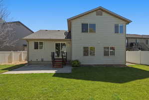 Expansive backyard featuring a manicured lawn, a concrete patio, and a two-story exterior with light-colored siding