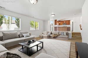 Spacious living area featuring light-toned flooring, multiple windows with blinds, and recessed lighting