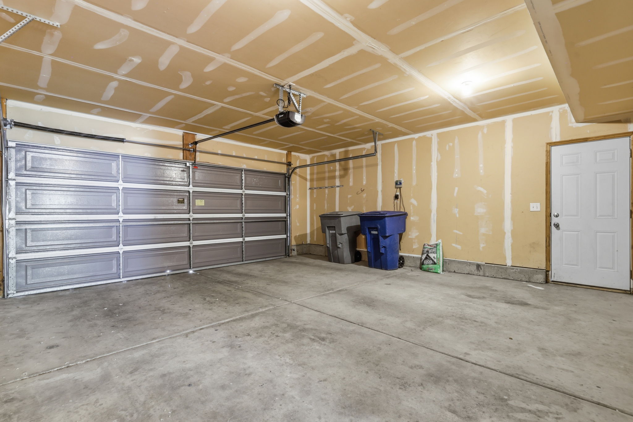 Spacious two-car garage featuring a concrete floor, a paneled overhead door, and an automatic garage door opener
