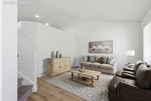 Spacious living area featuring light wood-finish flooring, recessed lighting, and a white color palette