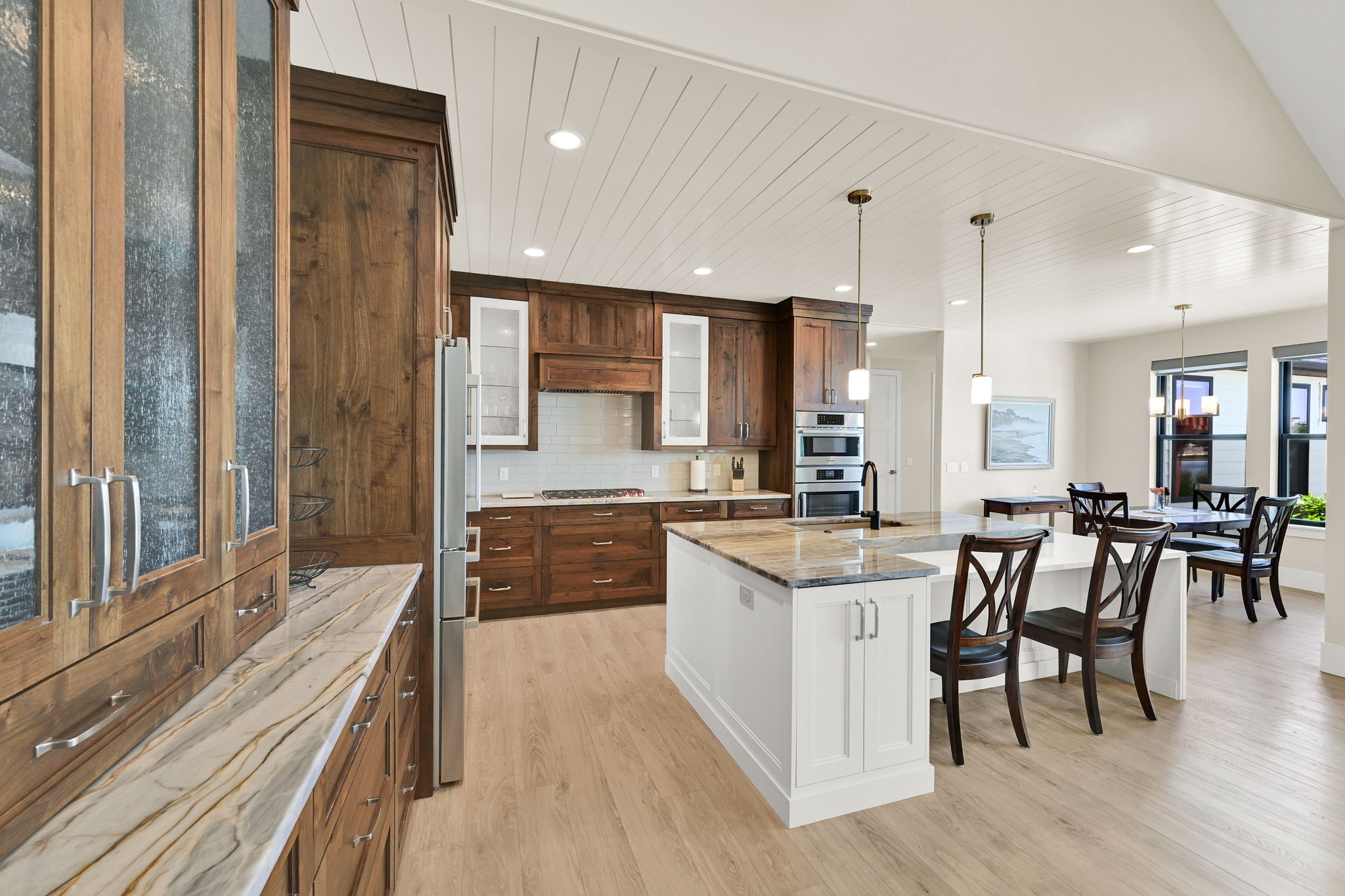 Gourmet Chef Style kitchen featuring wood-finish cabinetry, a large center island with a granite-style countertop, stainless steel appliances, and wood-finish flooring