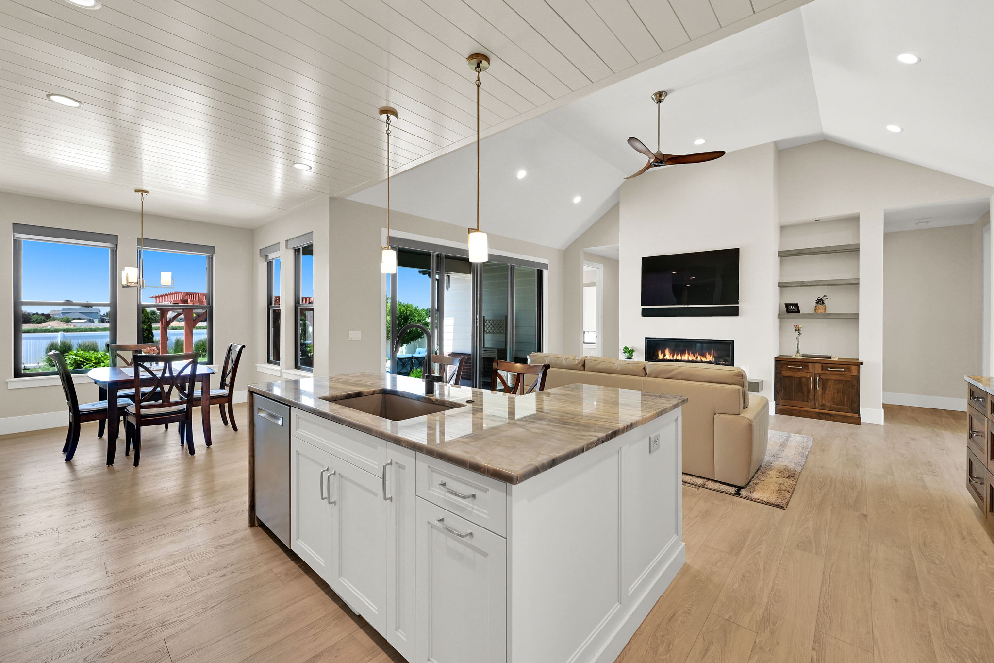 Open-concept living space featuring a kitchen island with stone countertop, stainless steel sink, and built-in dishwasher