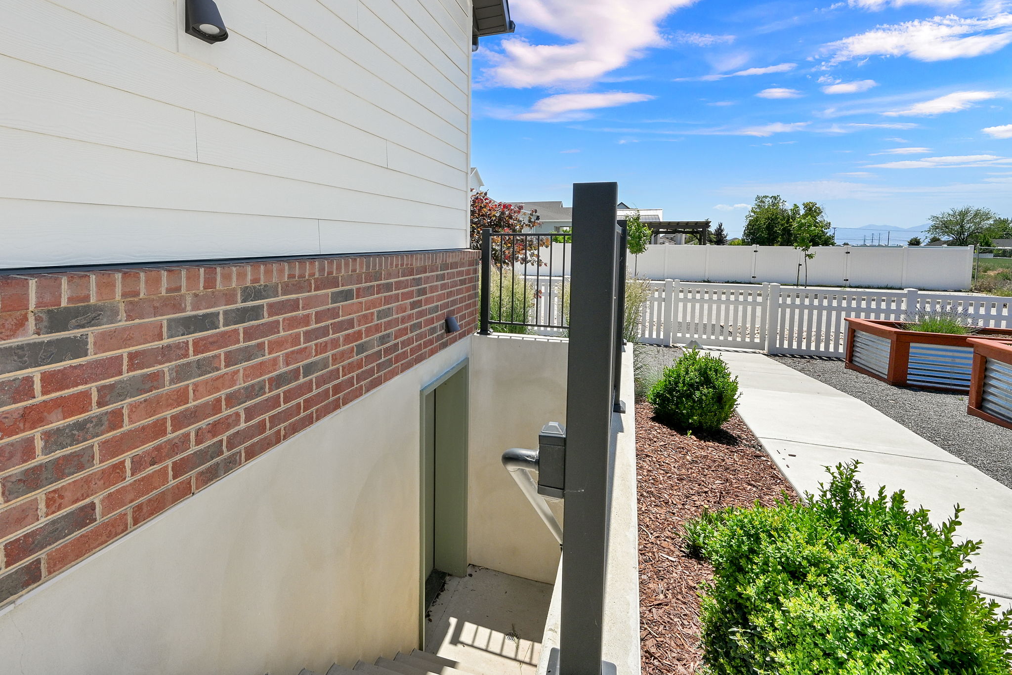 Exterior featuring white siding, brick veneer, and a daylight basement entry