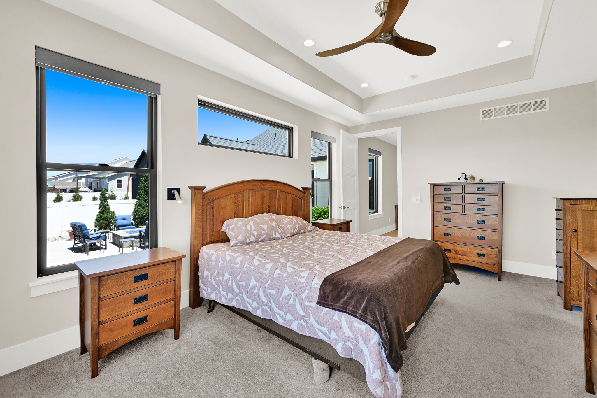 Bright bedroom featuring a tray ceiling with recessed lighting and a ceiling fan