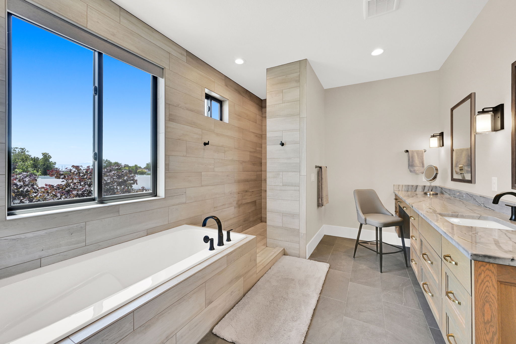 Soaking tub featuring matte black fixtures and a window with outdoor scenery