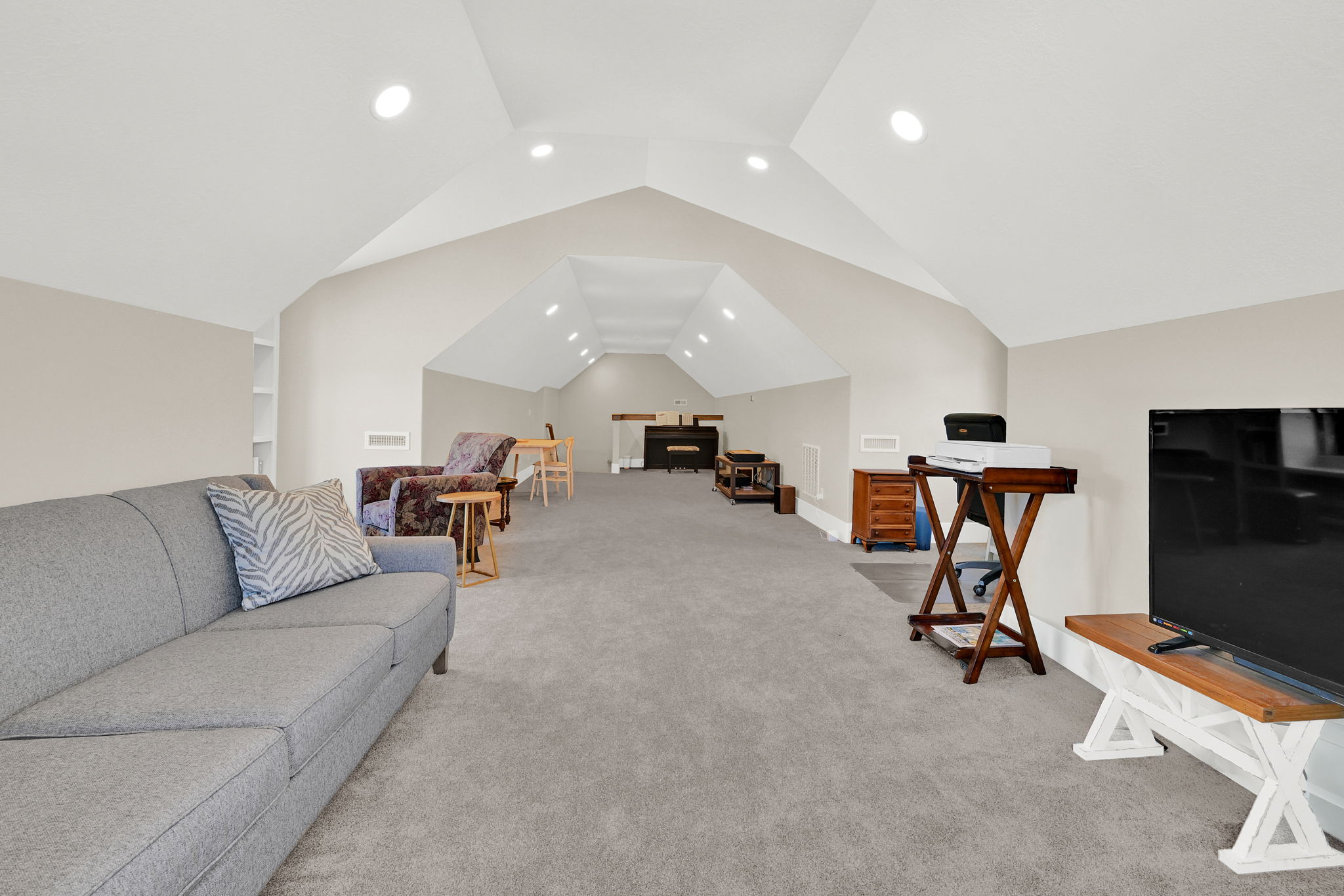 Spacious bonus room featuring vaulted ceilings, recessed lighting, neutral carpeting, and built-in shelving